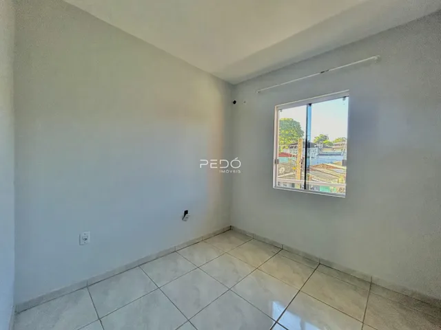 Ambiente interno de uma sala com piso de cerâmica e janela.