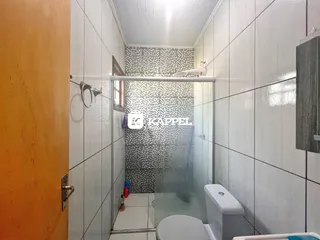 Banheiro com box de vidro e revestimento de azulejos brancos.