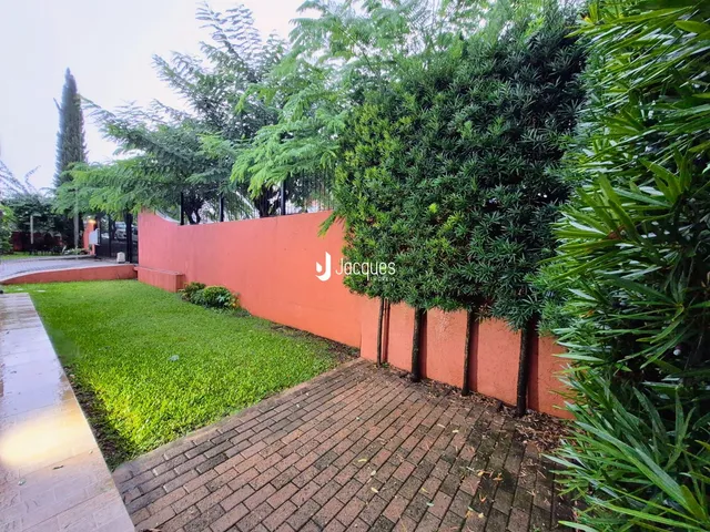 Vista da fachada de uma propriedade com muro e jardim.