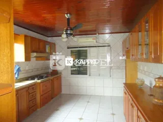 Foto interna da cozinha com armários de madeira e piso cerâmico.