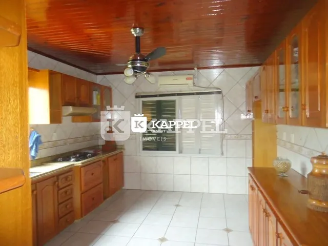 Foto interna da cozinha com armários de madeira e piso cerâmico.