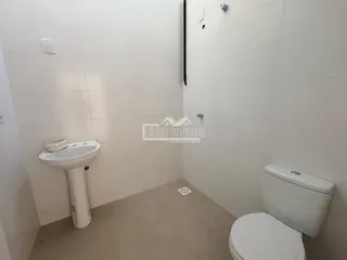 Foto de um banheiro interno com azulejos brancos e vaso sanitário branco.