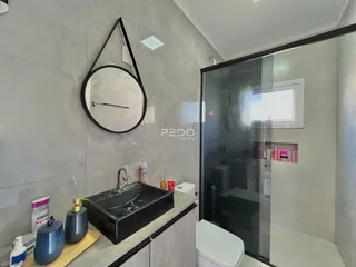 Banheiro com revestimento de azulejo e box de vidro.
