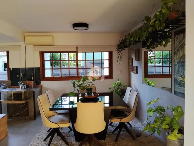 Foto de uma sala de jantar com mesa escura e cadeiras claras em um ambiente bem iluminado.