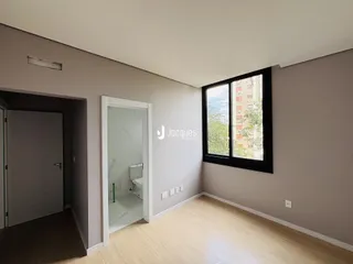 Interior de uma sala com piso de madeira e janela.