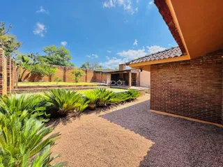 Vista externa de uma propriedade com parede de tijolos e paisagismo verde.