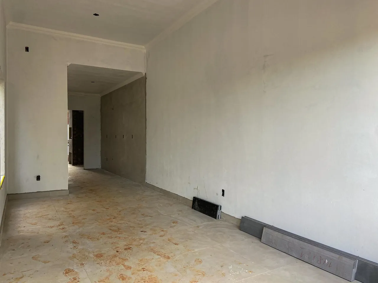 Hall de entrada com paredes brancas e piso de cimento.