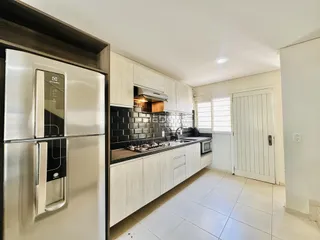 Cozinha moderna com armários brancos e revestimento preto.