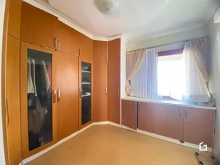 Quarto com armários em madeira e janela iluminada.