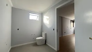 Foto de um banheiro com piso claro e vaso sanitário branco.