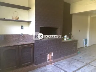 Vista de uma bancada de cozinha com armários escuros e uma coluna de parede texturizada.