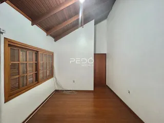 Interior de uma sala com piso de madeira e teto de madeira aparente.