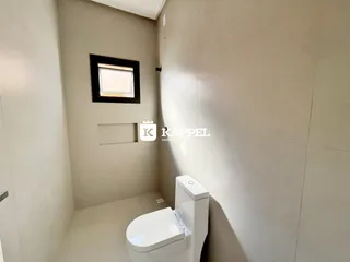 Foto de um banheiro simples com vaso sanitário branco e parede clara.