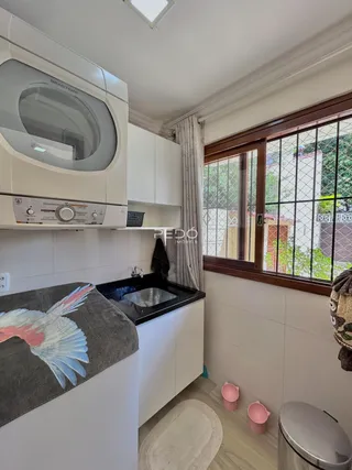 Vista da cozinha com armários brancos e bancada escura em imóvel no Brasil.