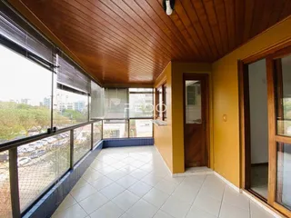 Vista interna de uma sala com piso de cerâmica e teto de madeira com vista para a paisagem.