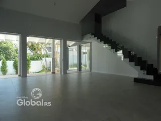 Espaço interno amplo com portas de vidro e escadaria moderna em uma residência.