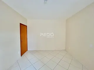 Ambiente interno de uma sala com piso de cerâmica e porta de madeira.