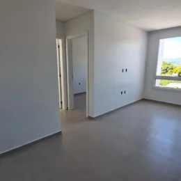 Hall de entrada com paredes brancas e piso claro.