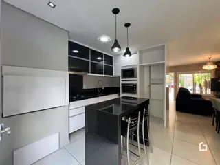 Vista da cozinha moderna com armários pretos e bancadas escuras.