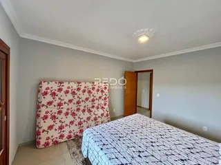 Quarto com cama de casal e paredes claras.