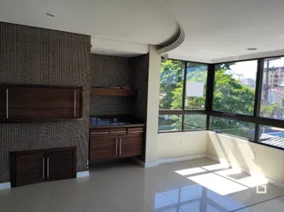A sala de estar apresenta paredes com papel de parede e grandes janelas.