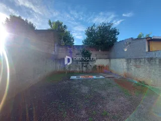 Vista externa de um pátio cercado por muros de alvenaria.
