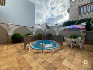 Piscina cercada com área de lazer e mobiliário externo.