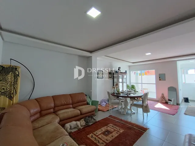 Sala de estar com sofá de couro marrom e tapete no interior da residência.