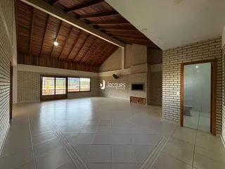 Interior de uma sala ampla com piso de cerâmica e paredes de tijolo aparente.