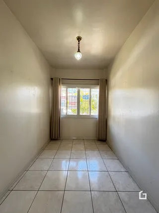 Corredor interno de uma residência com piso de cerâmica e paredes brancas.
