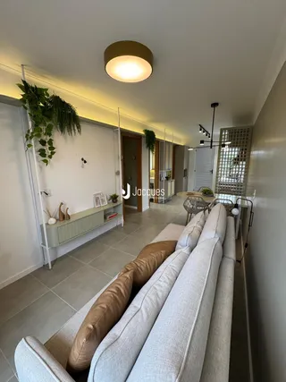 Sala de estar com sofá grande e piso de cerâmica clara.