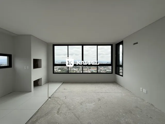 Ambiente interno de sala com grande janela oferecendo vista da paisagem urbana.