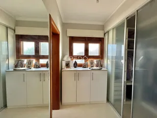 Vista de um corredor interno com armários brancos e detalhes em madeira.