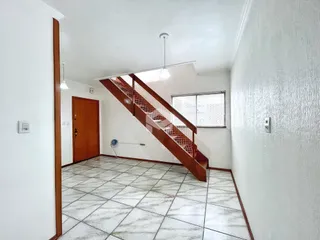 Hall de entrada com escada de madeira e piso de cerâmica.