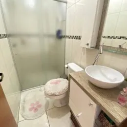 Foto de um banheiro com revestimento de azulejos brancos e louças brancas.
