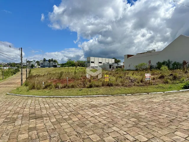 Vista externa de um terreno com paisagismo e construção no fundo.