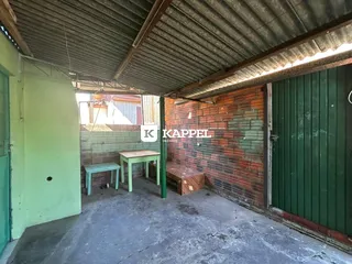 Área externa coberta com piso de concreto e parede de tijolos à vista.
