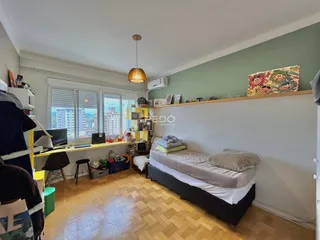 Quarto com paredes verdes e piso de madeira clara.