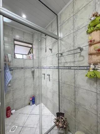 Foto de um banheiro com azulejos brancos e box de vidro.