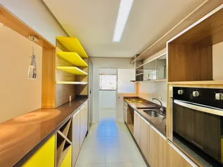 Vista de uma cozinha moderna com armários de madeira e piso claro.