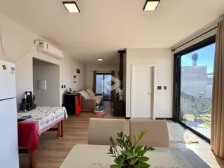 Sala de estar com piso de madeira e vista para o exterior.