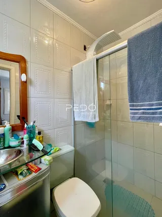 Foto do interior de um banheiro com box de vidro e vaso sanitário.