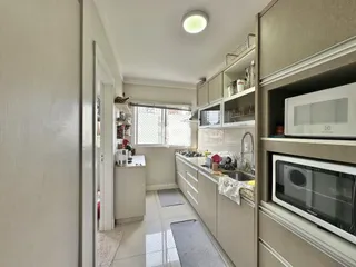 Cozinha moderna com armários brancos e piso claro.