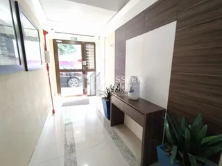 Corredor interno de uma residência com piso claro e paredes brancas.