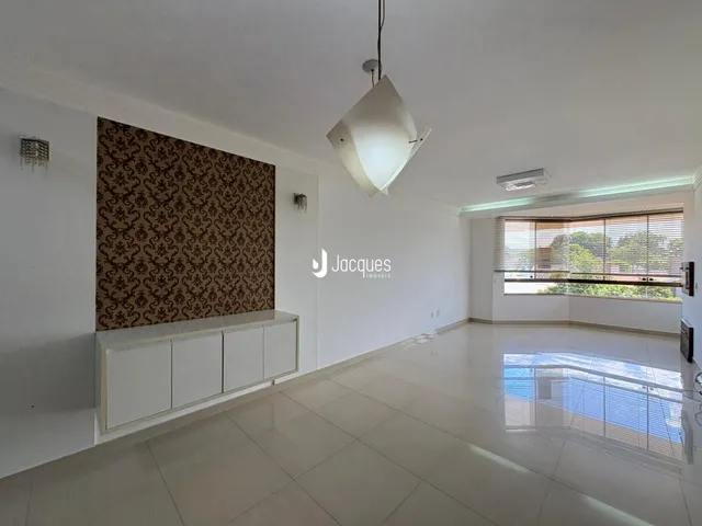 Ambiente interno de uma sala ampla com piso claro e parede decorada.