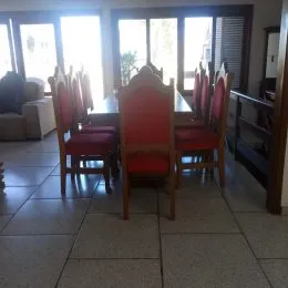 Uma sala de jantar com mesa e cadeiras vermelhas em um ambiente interno.