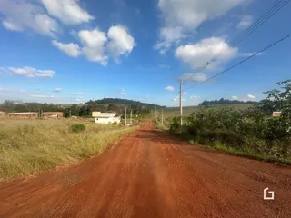 Uma estrada de terra vermelha atravessa uma paisagem rural no Brasil.