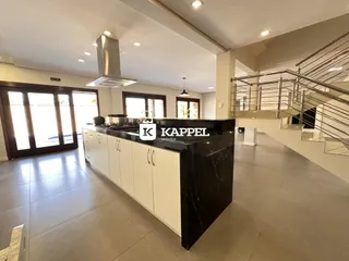 Cozinha moderna com ilha escura e armários brancos em um imóvel em Lajeado.