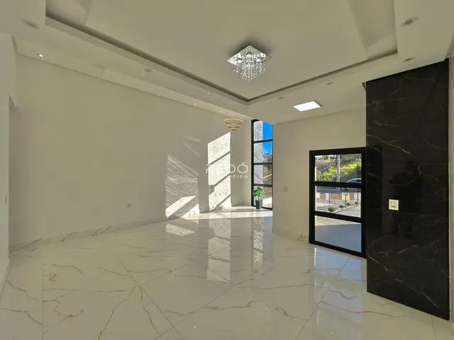 Sala ampla com piso de mármore claro e teto alto.