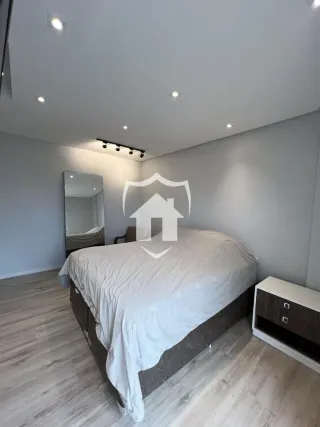 Quarto com cama e piso de madeira clara.
